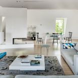 Evergreen czyli fotel Barcelona Miesa Van Der Rohe - klasyk w turkusach. Pod oknem drewniany stół i krzesła ze