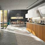 Fornirowane szafki kuchenne pasują do drewna w jadalni. SNAIDERO