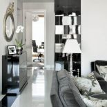 Fronty czarnej garderoby w korytarzu, wykończone na wysoki połysk, sprawiają, że meble mają głębię, są