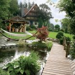 Górny taras ogrodu to szeroki trawnik z altaną i staw z kaskadą, wyglądającą jak górski potok.