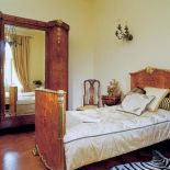 Intarsjowana wieloma gatunkami drewna ogromna szafa z lustrem i empirowe łoże z ozdobione czeczotem i złoceniami.