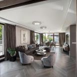 Kryształowe plafony Andromeda od Marchetti w salonie odbijają sączące się przez duże okna naturalne światło.