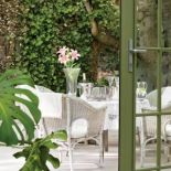 Jasna posadzka i białe meble ogrodowe pięknie komponują się z intensywną zielenią.