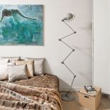 Jedyny kolorowy akcent w beżowo-szarej sypialni to obraz Mariusza Andryszczyka. Obok łóżka stoi kultowa lampa