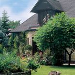 Kamienny dom otacza piękny ogród. Pejzaż wymyślony przy sztalugach