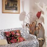 Kanapa z koronkową kapą, wieszak w kształcie drzewa i kolekcja drewnianych lasek.