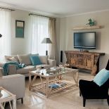 Kremowa, obita surowym płótnem kanapa okazała się dobrym towarzystwem dla kolonialnej komody.