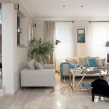 Kremowe sofy, fotele i kawowy stolik z turkusowymi dodatkami.