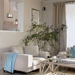 Kremowe sofy, fotele i kawowy stolik z turkusowymi dodatkami.