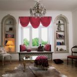 Kryształowy żyrandol w otoczeniu poduszek i grubych tkanin.