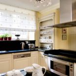 Kuchenne szafki w angielskim stylu przykryto blatem z czarnego kamienia. Z klasyczną formą mebli kontrastuje najnowsze agd.