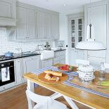 Kuchnia urządzona na biało z drewnianymi elementami.