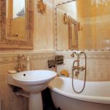 Ła­zien­ka w ko­lo­rze zsza­rzałe­go różu, wyłożo­na ja­snym tra­wer­ty­nem Bot­ti­ci­no i Ros­so Ve­ro­na, z