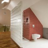 Łazienka oddzielona ścianą z luksferów.