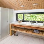 Łazienka w drewnie. Umywalki umiejscowiono pod długim oknem.