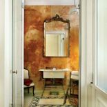 Łazienkę od sypialni oddzielają wysokie szklane drzwi. Stiuk, mozaika, francuskie lustro, stary fotel, biblioteczne schodki