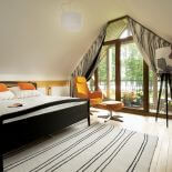 Łóżko w sypialni jest ze sklepu Habitat, pomarańczowy fotel z podnóżkiem z Ikea.