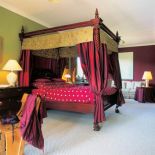 Łóżko z baldachimem. Na zielonym dywanie