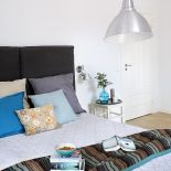 Łóżko z ruchomym zagłówkiem to NAP, szklany wazon-butla z Meubles De Charme. Poduchy, narzuta w sypialni - Malabelle.