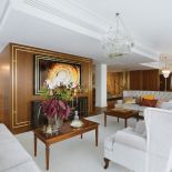 Do orzechowego drewna na podłodze i ścianach architekci wybrali kremowe sofy i dywany, dzięki czemu salon jest lżejszy i