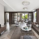 Stonowaną kolorystykę salonu w beżach i szarościach ożywiają błękitne motywy: sukienka kobiety w kapeluszu na