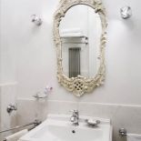 Lustro w rzeźbionej ramie czyni ją elegancką.