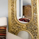 Lustro w złotej ramie dodaje sypialni blasku.