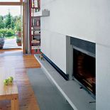 Minimalistyczny kamienny kominek komponuje się z drewnianą podłogą.