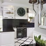 Mocne kontrasty: do białych szafek - czarny granitowy blat i czarny zegar.