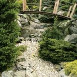 Mostek nad kamiennym strumieniem. Tarasowy ogród otoczony naturą