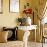 Na białej konsoli stoi lampka i wazon.