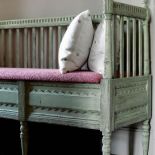 Na drewnianej ławie leżą poduszki w grochy.