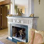 Na kominku stoją złocone dekoracje. Rezydencja strojna w antyki