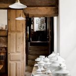 Na komodzie pod oknem stoi kolekcja białej porcelany.