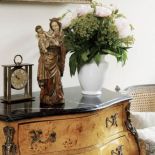 Na komodzie stoi zegar i figurka Matki Boskiej.