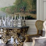 Na konsoli stoją różnorodne świeczniki.