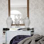 Na lustrzanej konsoli stoją dekoracyjne naczynia.