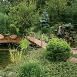 Na pomoście stoją fotele i stolik. Tarasowy ogród otoczony naturą