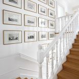 Na ścianie przy schodach symetrycznie powieszone obrazy.