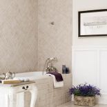 Na ścianie w łazience trawertynowe płytki i białe panele.