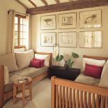 Na ścianie wisi kolekcja obrazków. Kamień i drewno w jednym domu