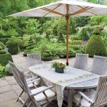 Na tarasie stół, krzesła i parasol - jadalnia pod chmurką.