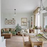 Na zielonej kanapie leżą poduszki obszyte tkaniną w róże.