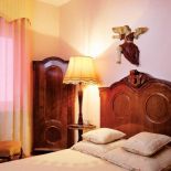 Nad drewnianym łóżkiem wisi aniołek.