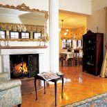 Nad kominkiem wisi lustro w zdobionej ramie.