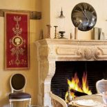 Nad kominkiem wisi zegar. Farma pełna pięknych staroci