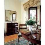 Nad komodą wisi lustro w zdobionej ramie.