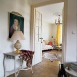 Nad konsolą wisi portret w zdobionej ramie.