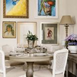 Nad okrągłym stołem wisi kolekcja obrazów.