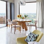 Nad orzechowym stołem, zrobionym na zamówienie, lampa Prandina. Fotel Mishell z Noti.